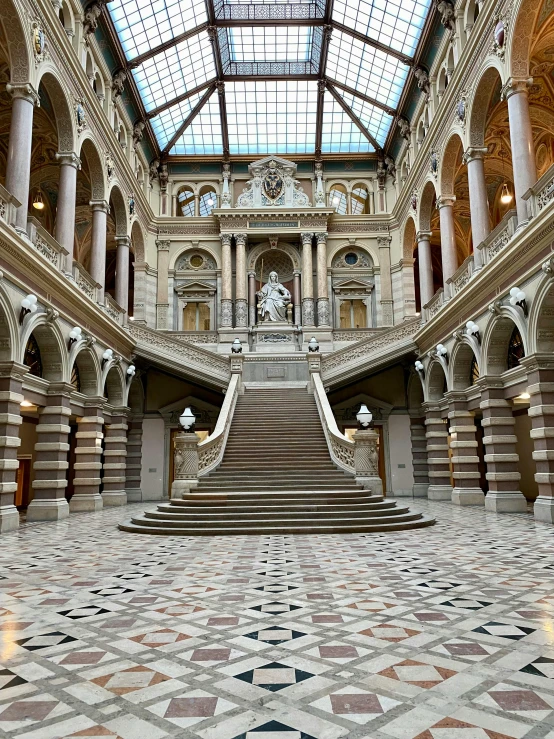 the large open building has marble pillars and a glass ceiling