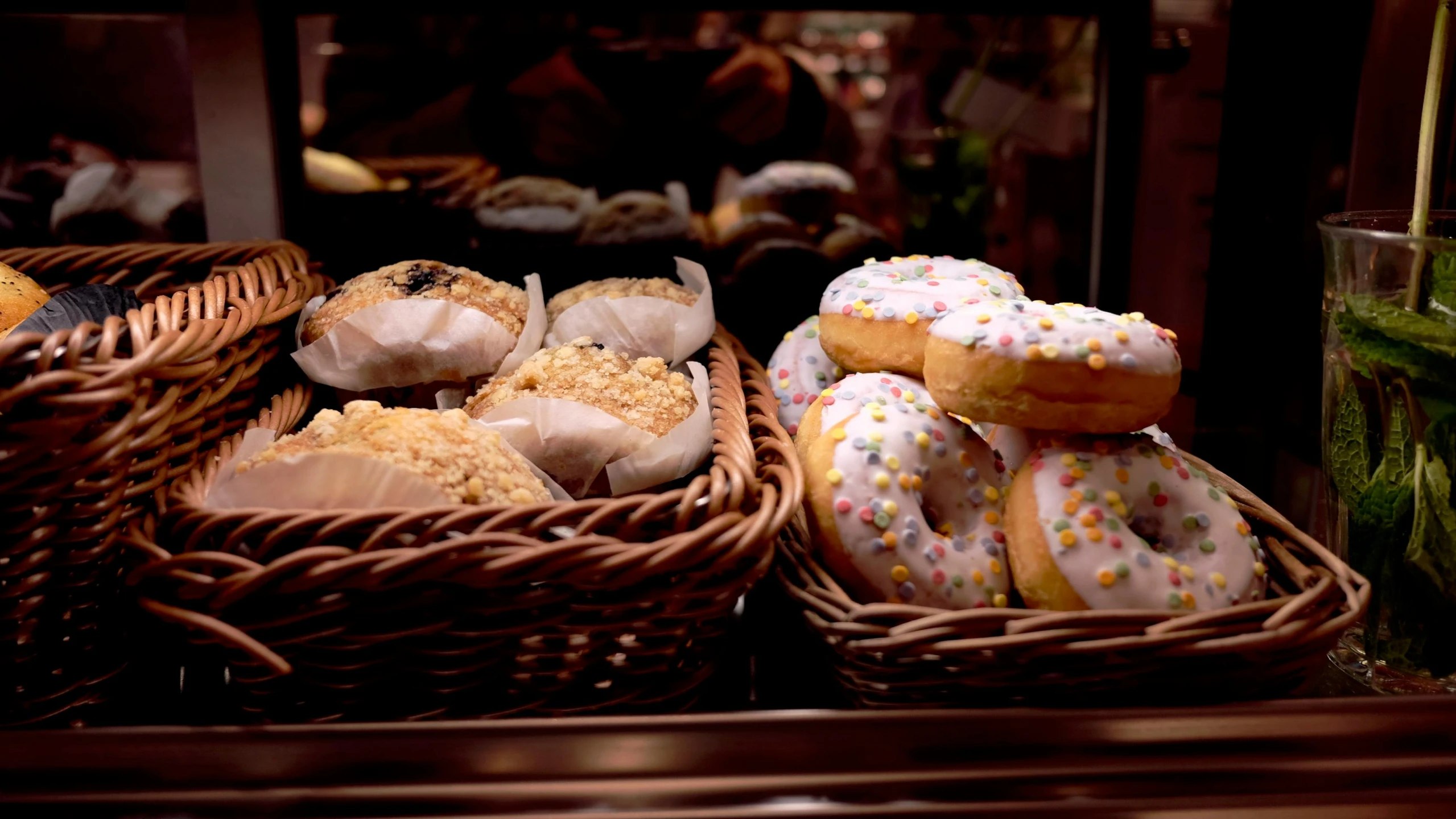 a variety of donuts in baskets on display at a bakery