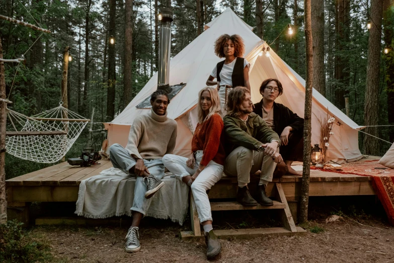 a group of people are sitting in a wooden platform by a tent