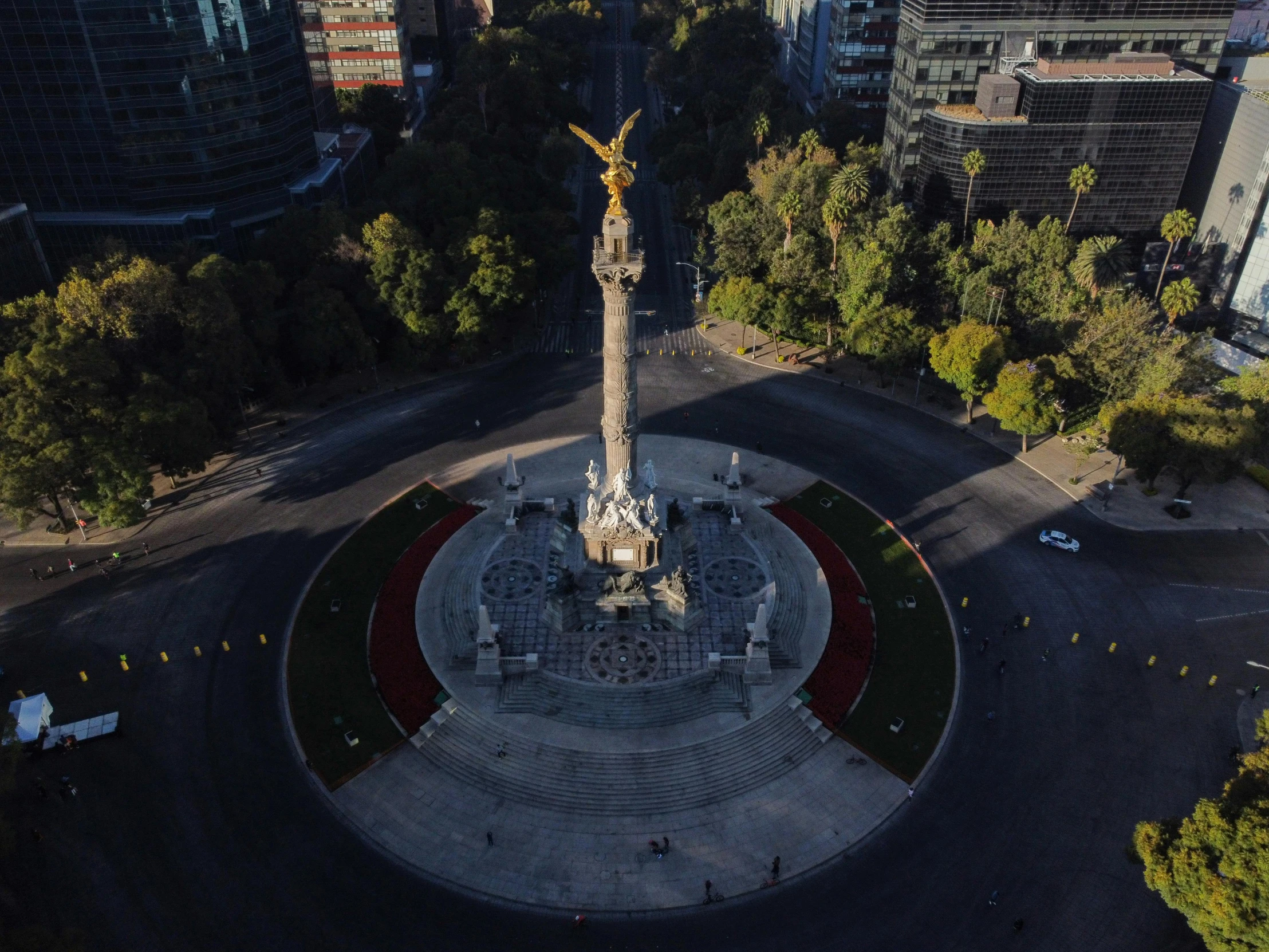 a monument stands in the middle of an intersection in front of many high rise buildings