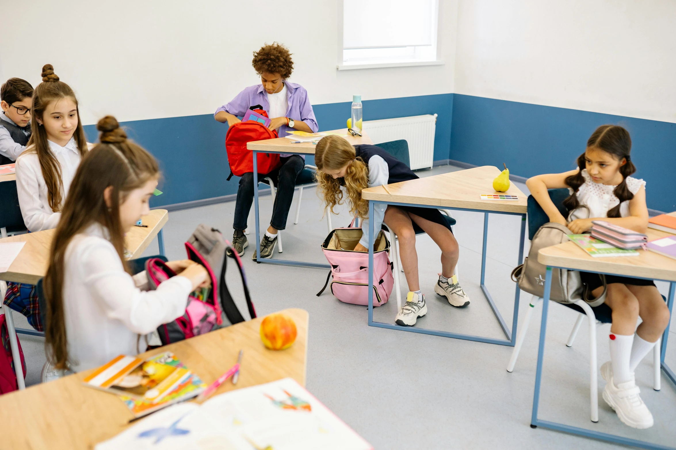 children are sitting at desks with lunch boxes on them