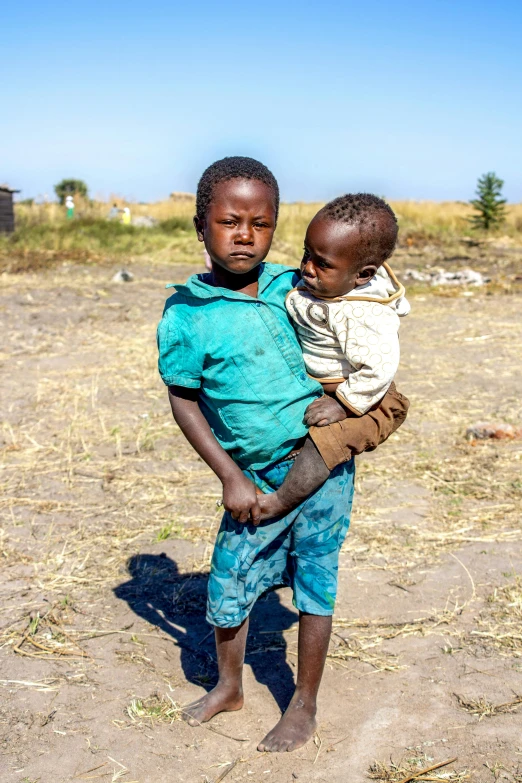 two young children holding each other and one has a towel on his shoulders