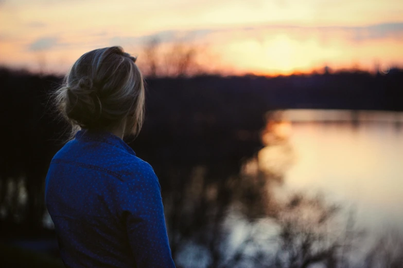 a person standing near water watching the sun rise