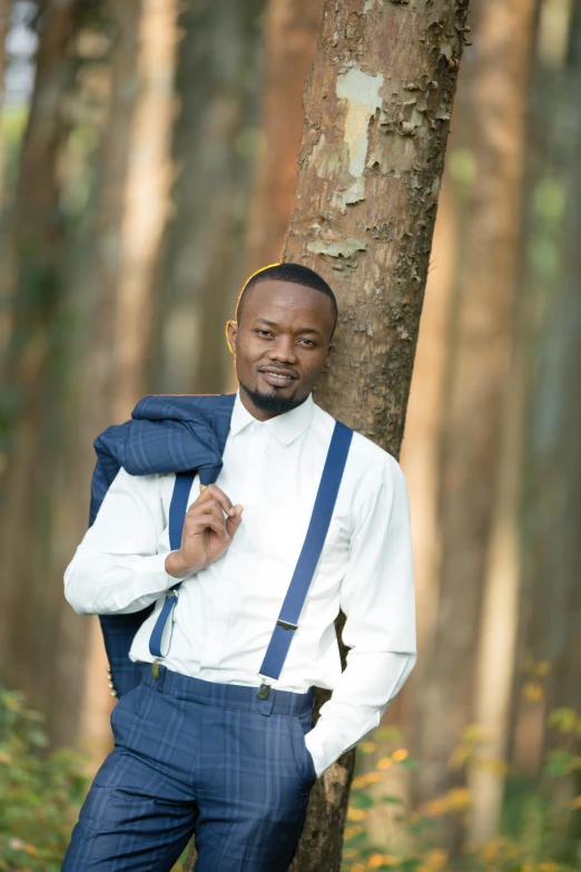 the man is standing beside a tree in a wooded area