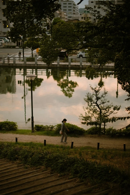 a man standing by the water and under the trees