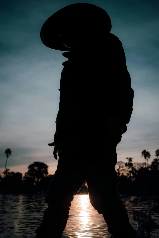 silhouette pograph of a man standing near water