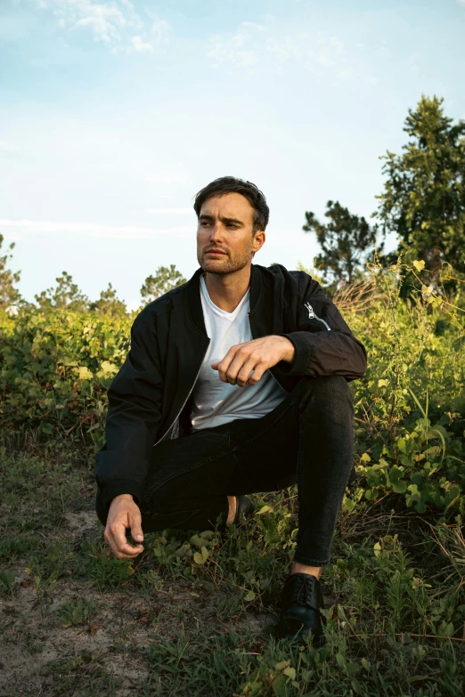 a man is sitting on some grass with a blue sky in the background