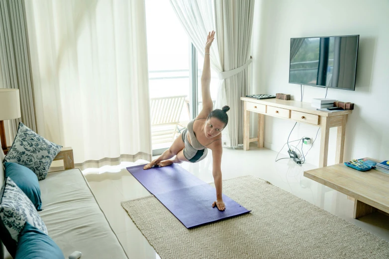 a woman doing yoga in her room in front of the tv