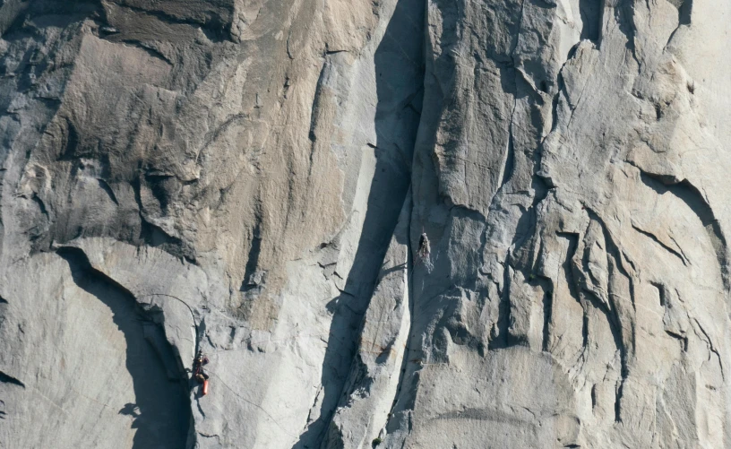 climbers ascending up and down a tall rocky mountain