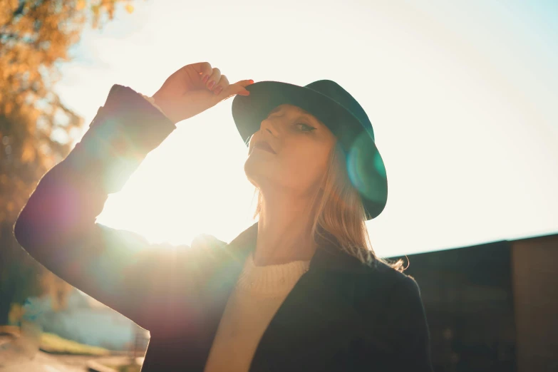 a beautiful young woman wearing a hat next to trees