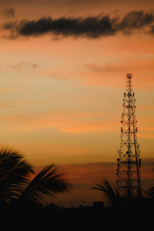 a tall radio tower in the middle of a sunset