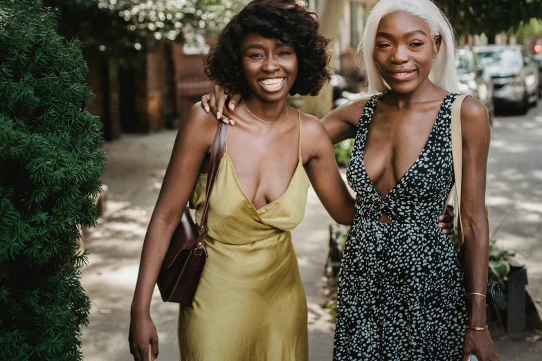 two women posing on a street, smiling for a camera