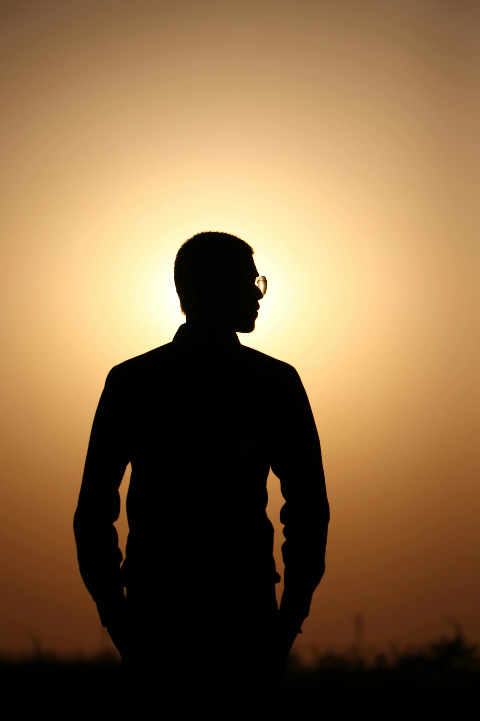 a silhouetted man standing next to the setting sun