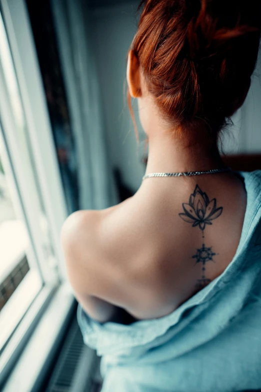 a woman looking out the window with her back turned towards the camera