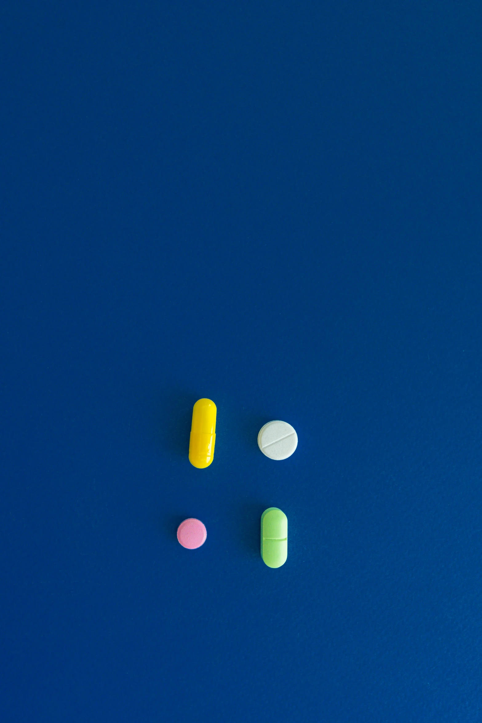 a group of multi - colored pills lie against a blue background