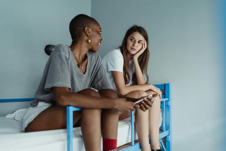 two people sitting on top of a small bunk bed