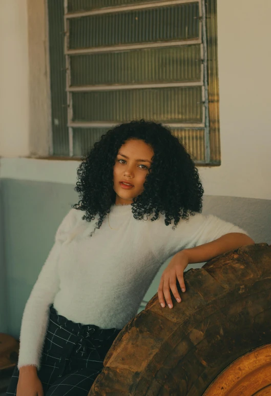 a woman is posing on a sofa with a large round wooden item