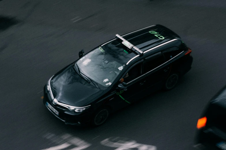 the black vehicle with green letters is driving down the street