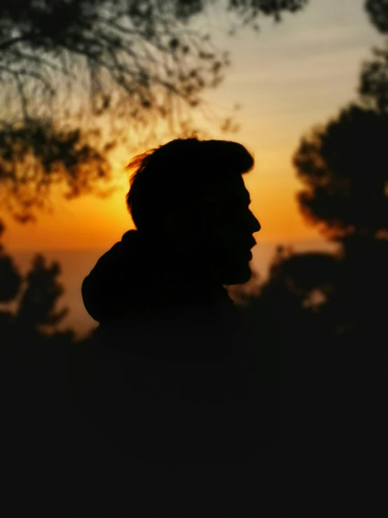 a man silhouetted against the sunset wearing a hat