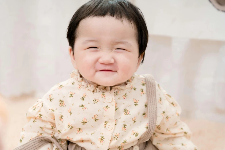 a smiling little girl is wearing a brown flower print shirt