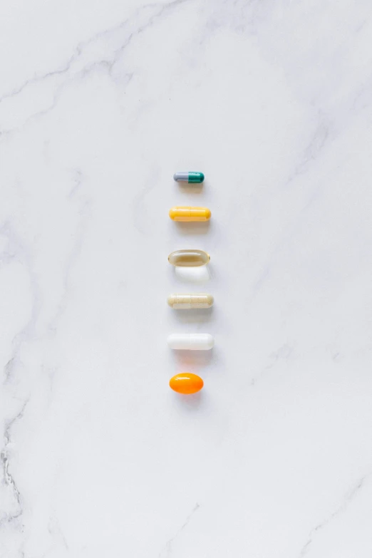 four pills arranged in a row on top of a marble surface