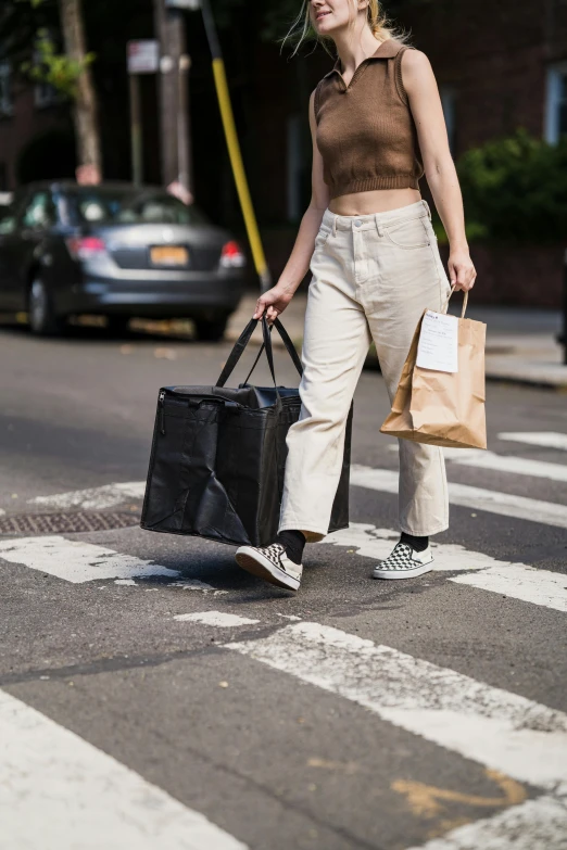 woman holding bags cross the street in a crosswalk