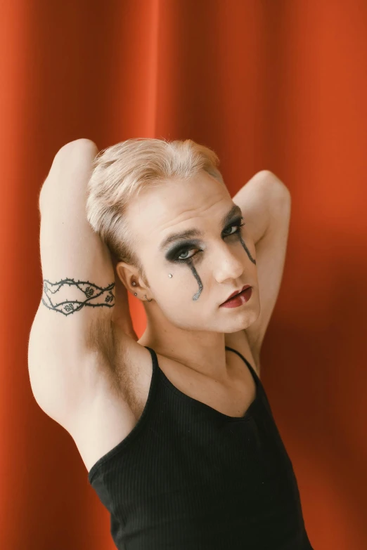 a woman with black paint on her face, standing with her arm around her head