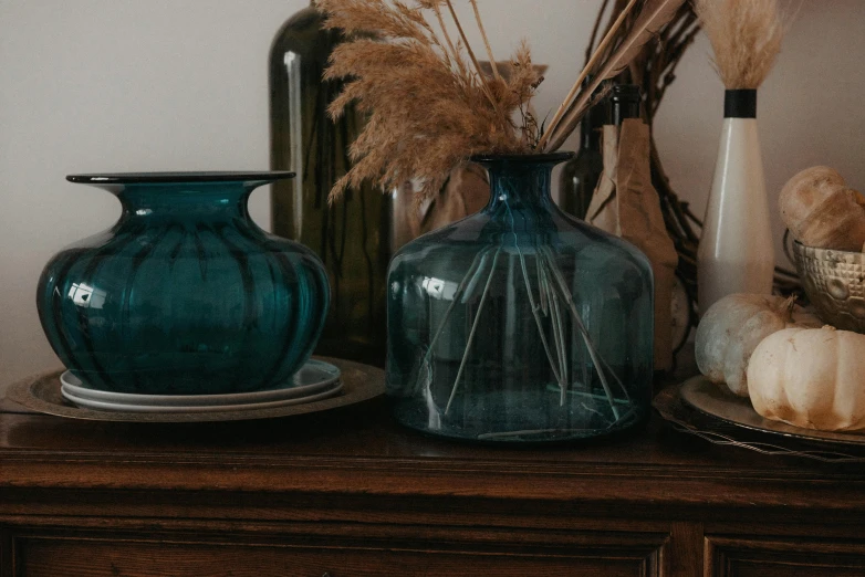 some vases and dried flowers are placed on a mantle