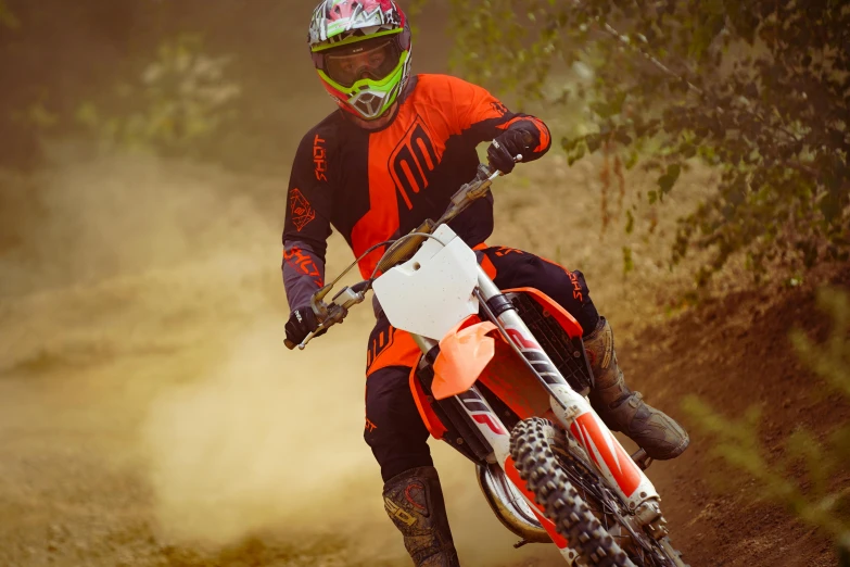 a motocross rider is on an orange dirt bike