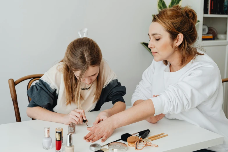 two women making cosmetics at a white table