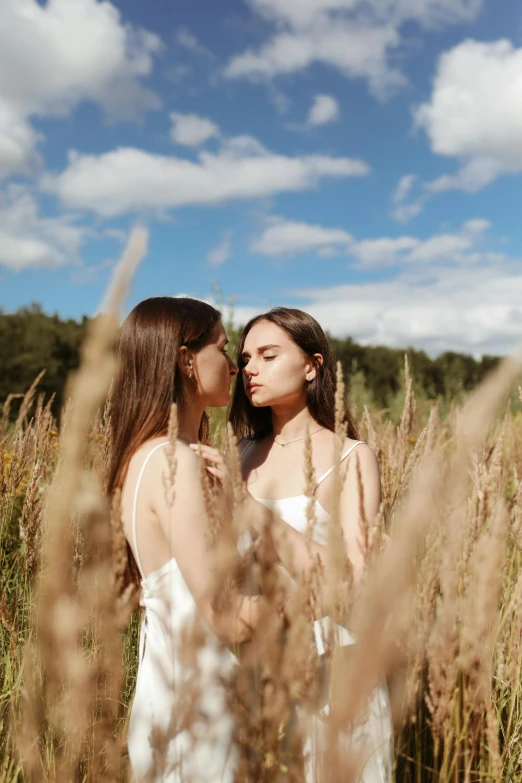 two young women standing in a tall grass field