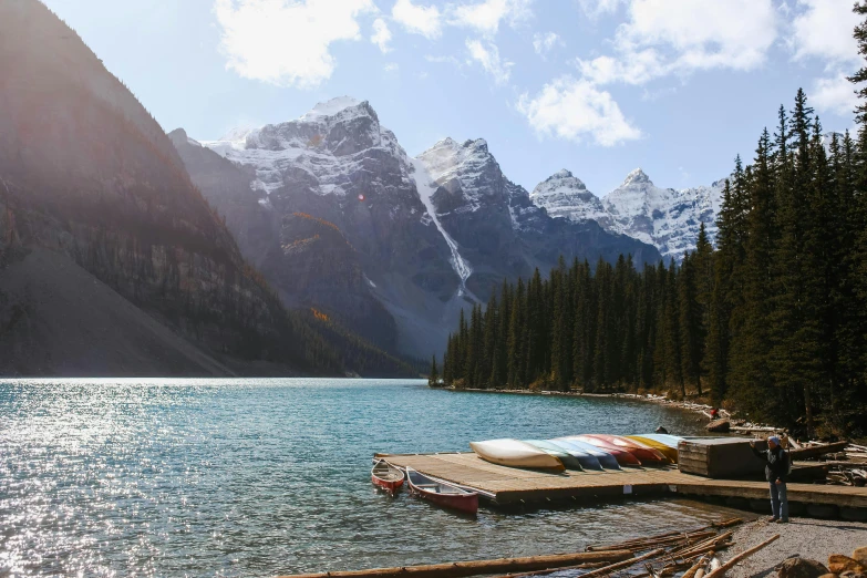 some canoes and kayaks tied up at the edge of a lake