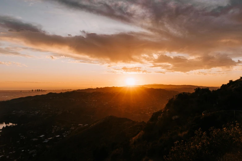 the sun is setting over a mountain with lots of trees