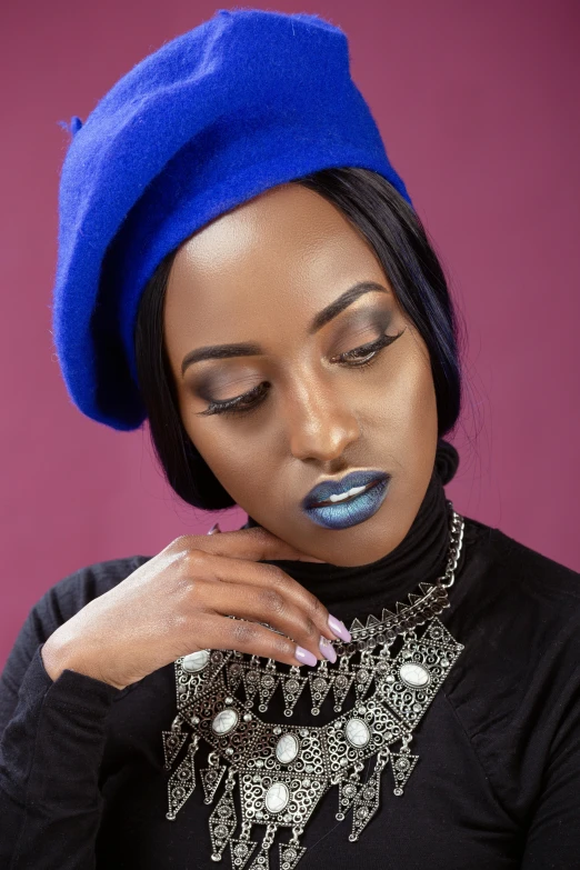 a woman with black makeup wearing a blue hat and necklace