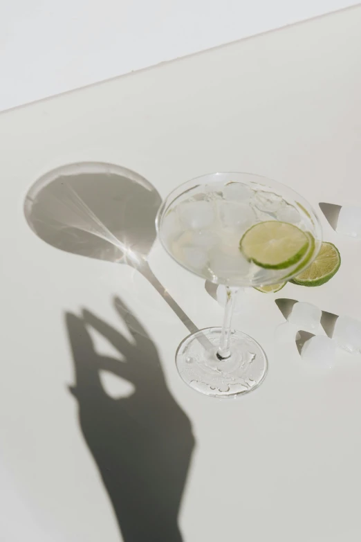 the shadow of a man's hand behind a martini glass