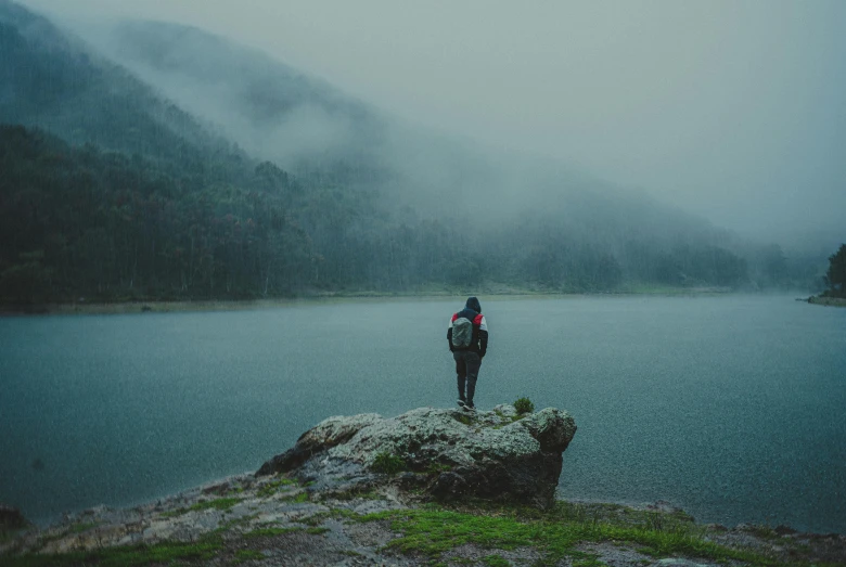 a woman standing on a rock by the water