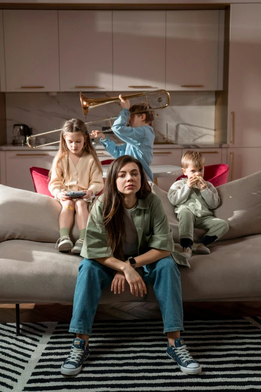 a  is sitting on a couch while her two children are sitting on the couch and one of them is holding a trombone