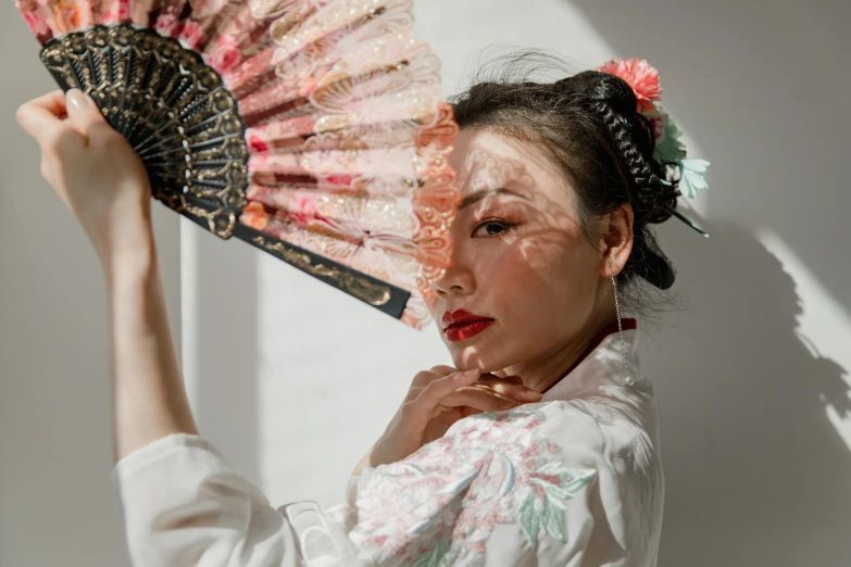 a woman in a traditional oriental dress holding an elaborate fan