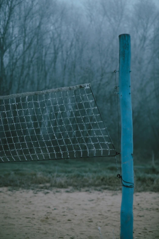 a net sitting by a field in front of trees