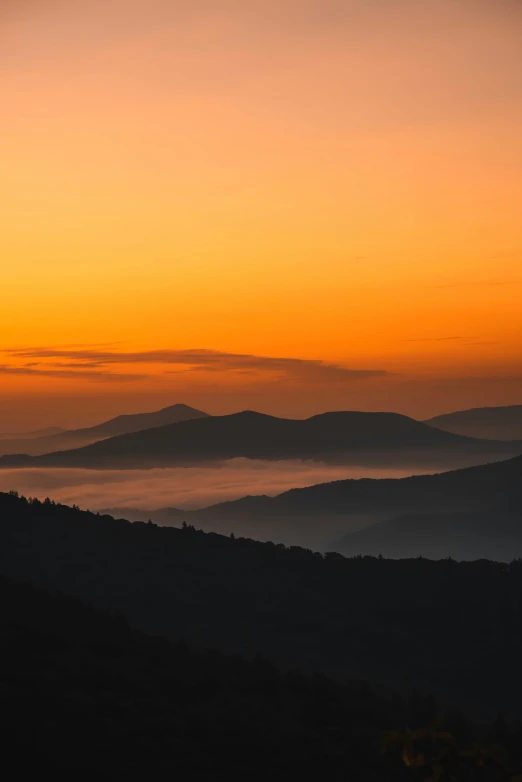 the silhouette of mountains at sunset with fog in the valleys