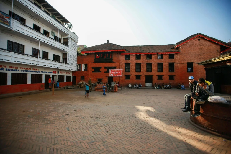 people sit on benches and play basketball outside buildings