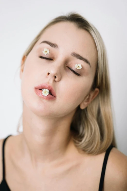 a woman with her eyes closed and daisies in the air