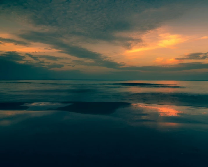 the sunset is shining brightly over the ocean and a rocky shore