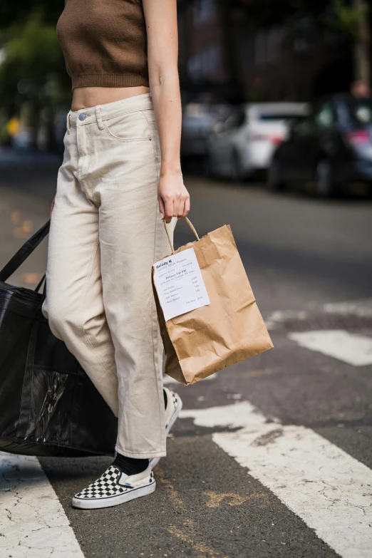 a person carrying two brown bags on a city street