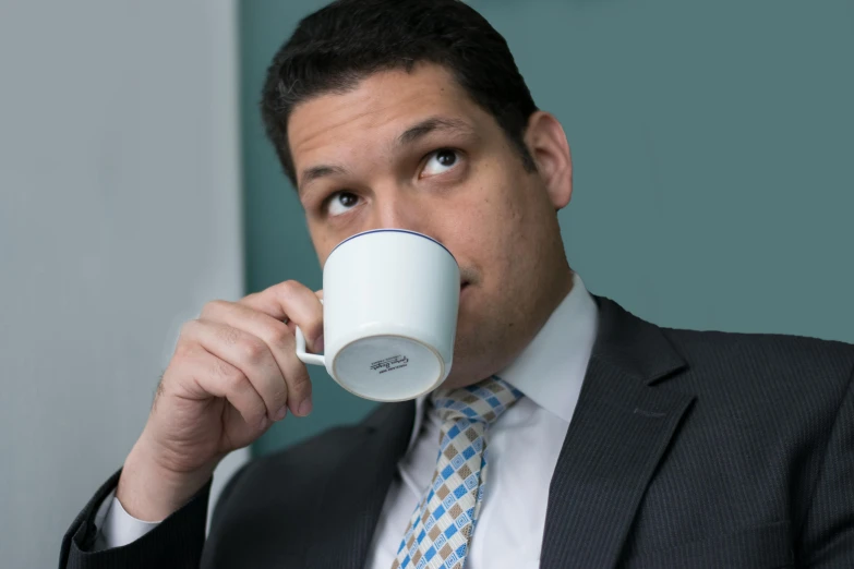 a man in a suit drinking from a cup