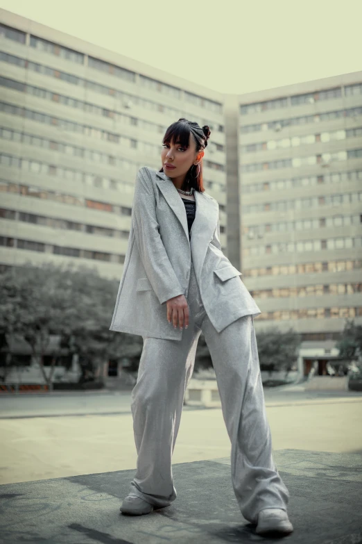 a woman standing next to a building and wearing a suit