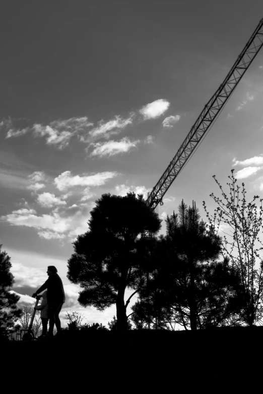 a man standing under a crane near trees