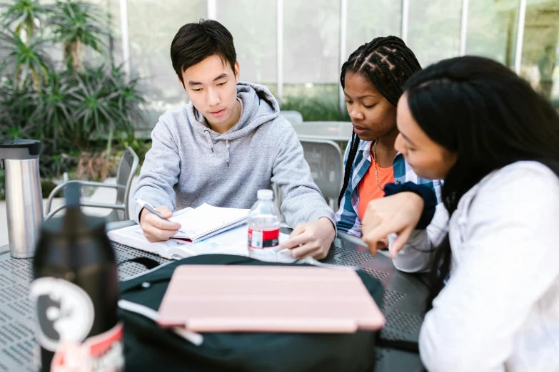 three people sitting at a table looking at paper