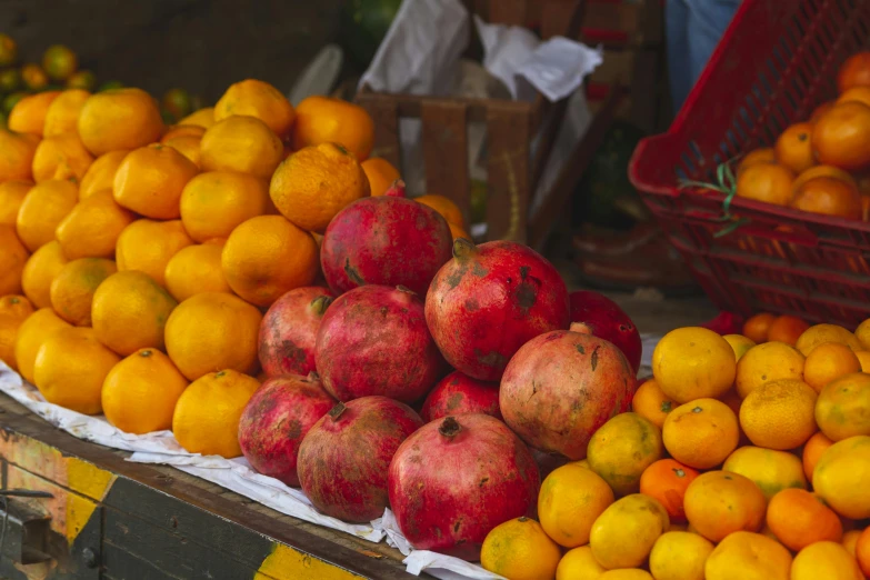 several pomegranates sit on top of each other, in boxes and behind them, at a farmers market