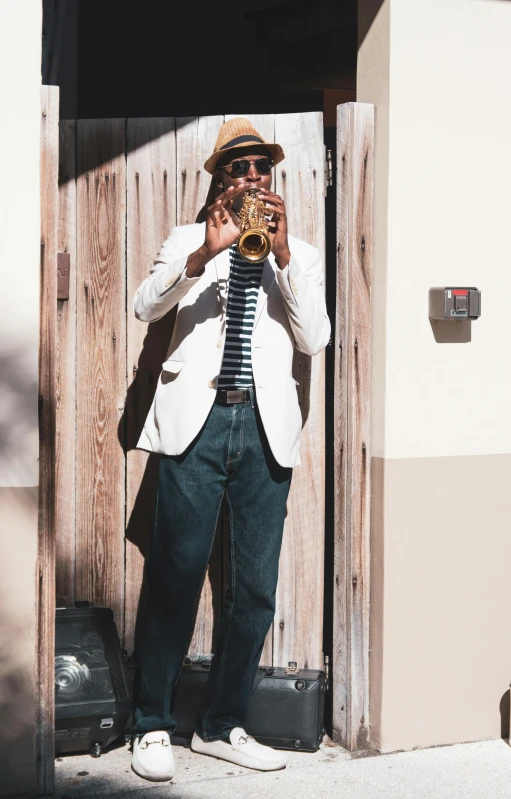 a man in jeans, shirt and jacket holding his instrument